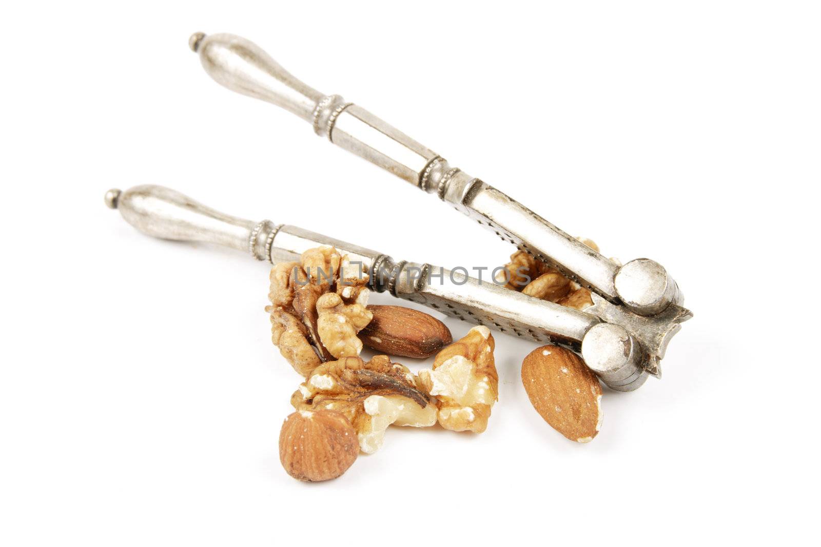 Assorted mixed nuts with a silver nutcracker on a reflective white background