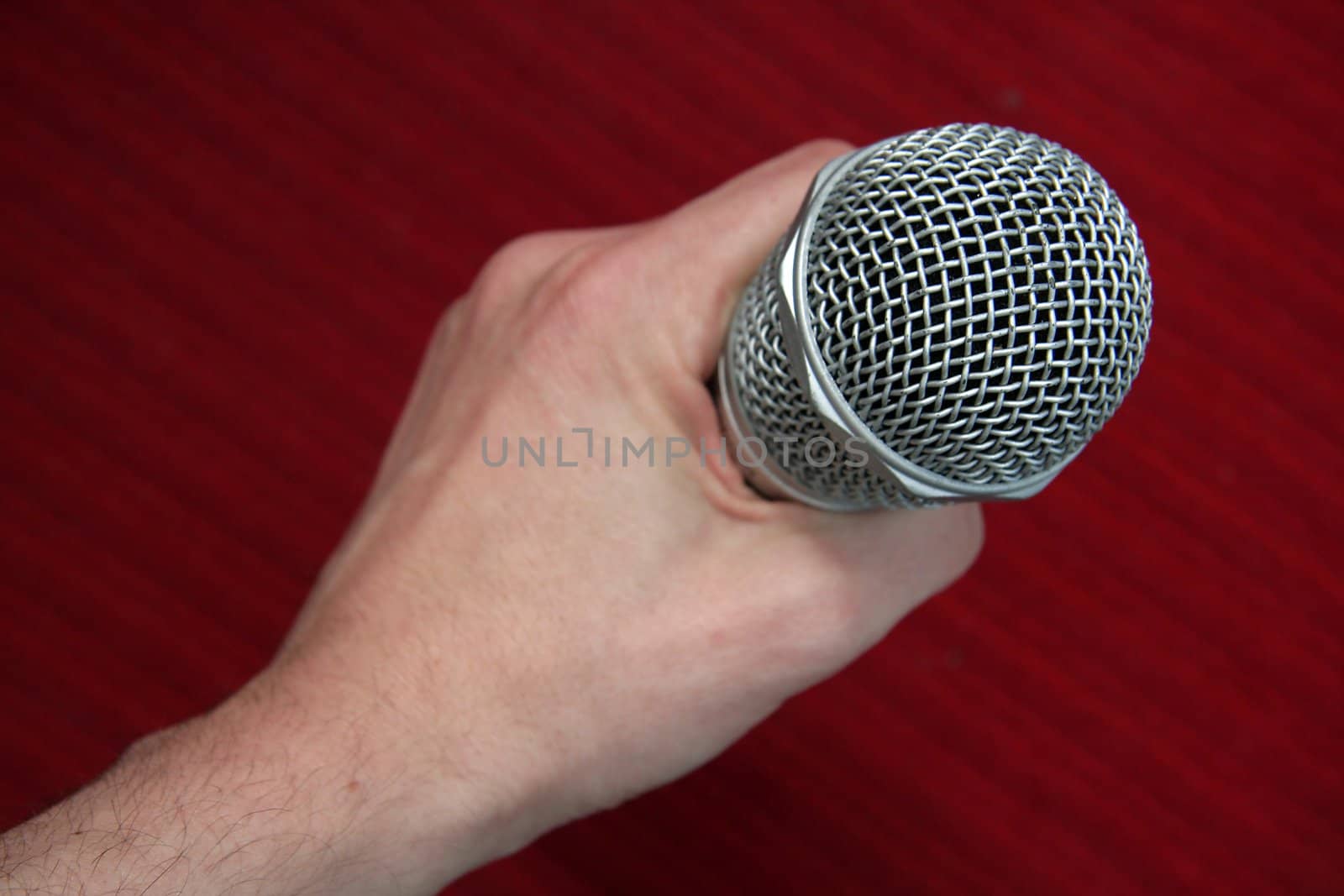 steel microphone in man hand, red background