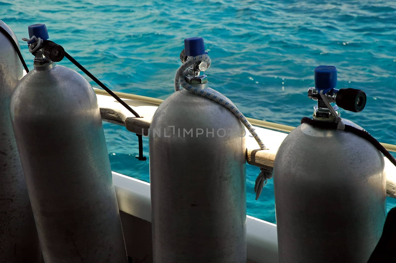 several scuba cylinders on boat, water in background