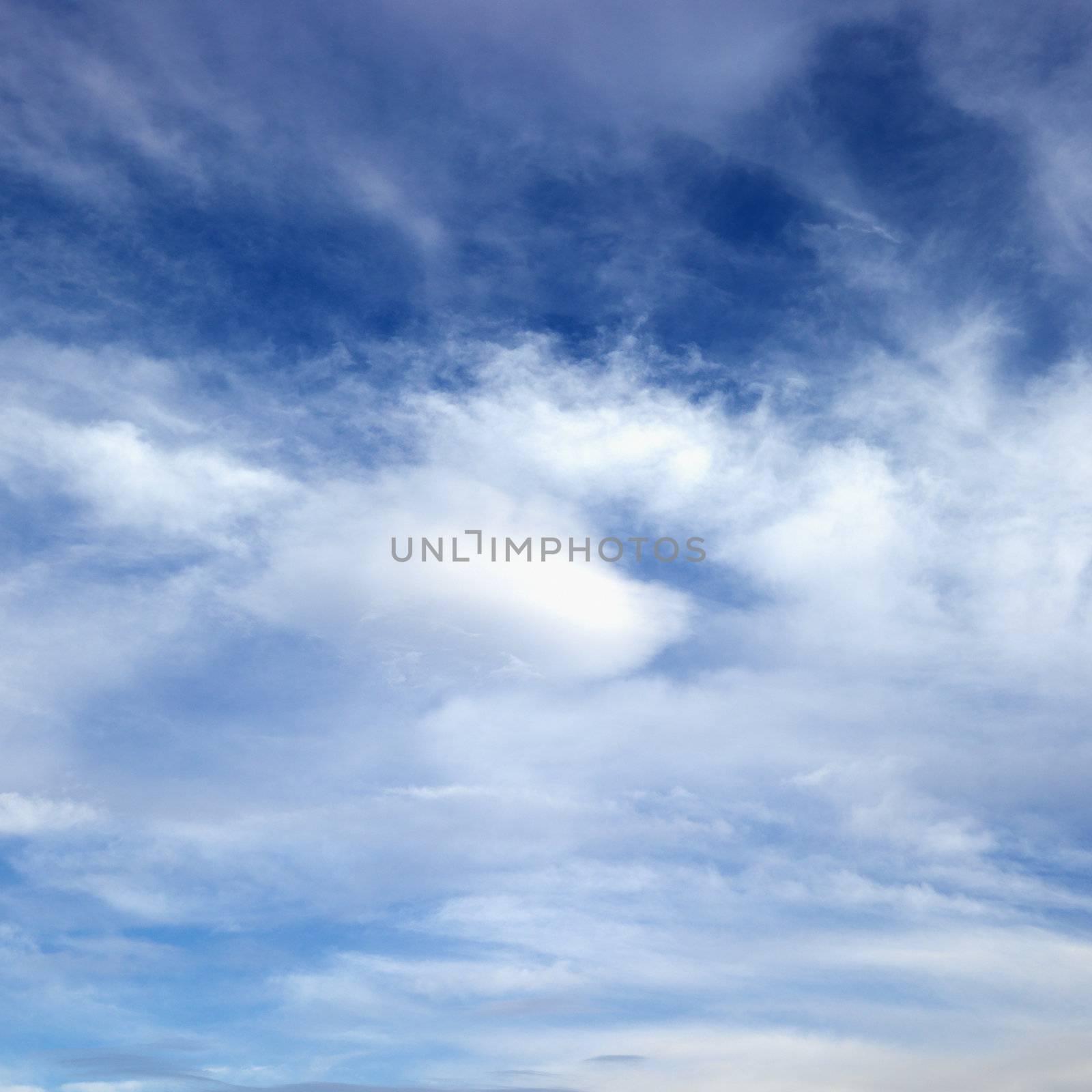 Wispy cloud formations against clear blue sky.