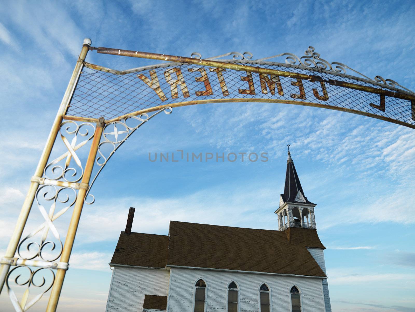 Metal cemetary entryway with small church.