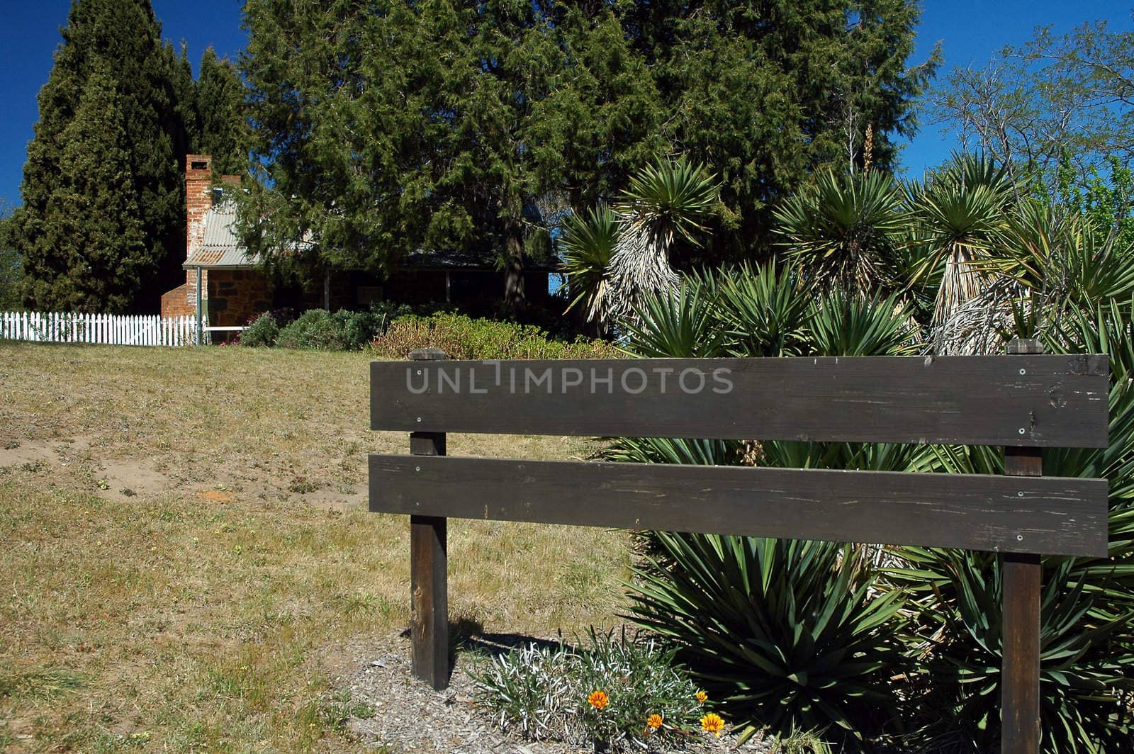 empty wooden sign in front of an old australian cottage
