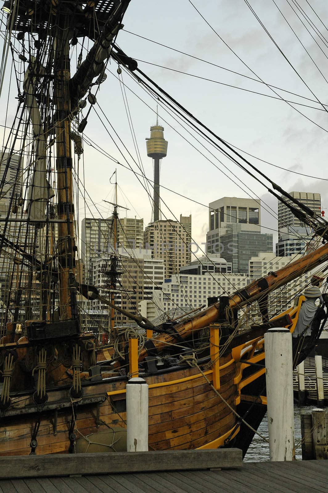 old wooden sailboat anchoring in Darling Harbour in Sydney; sydney tower in background