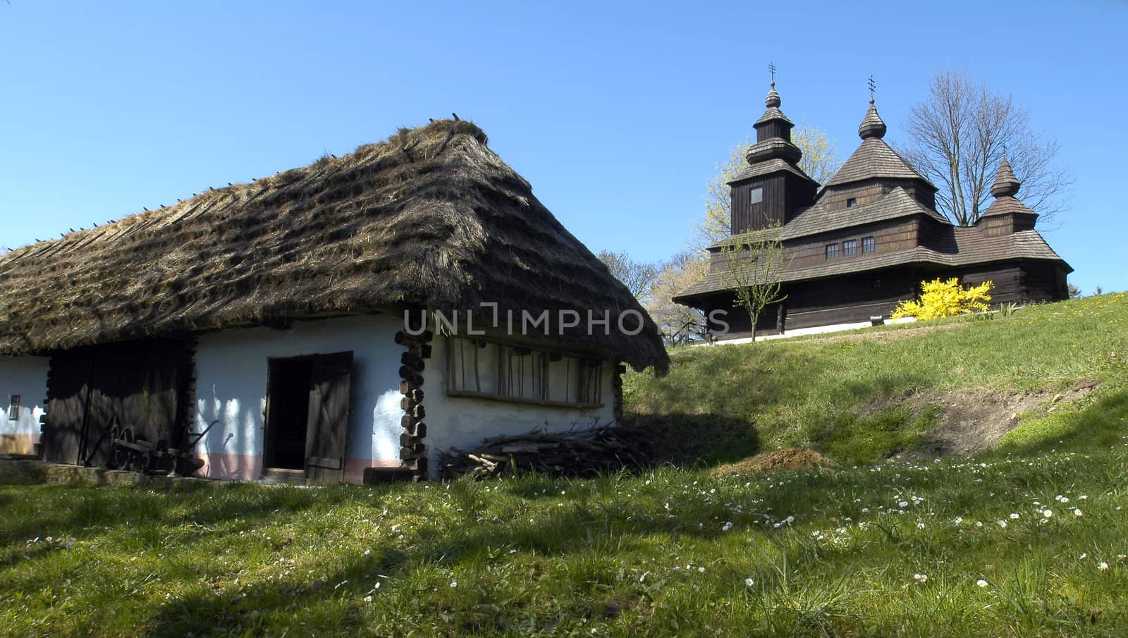 old wooden house with straw roof and  well-preserved wooden church in an outdoor museum in city Humenne - east Slovakia;