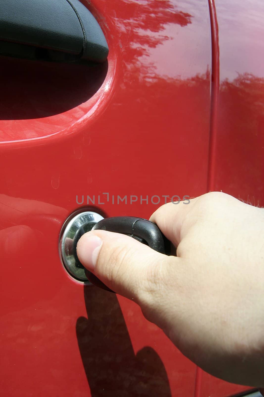 detail photo of a mans hand locking up a red car