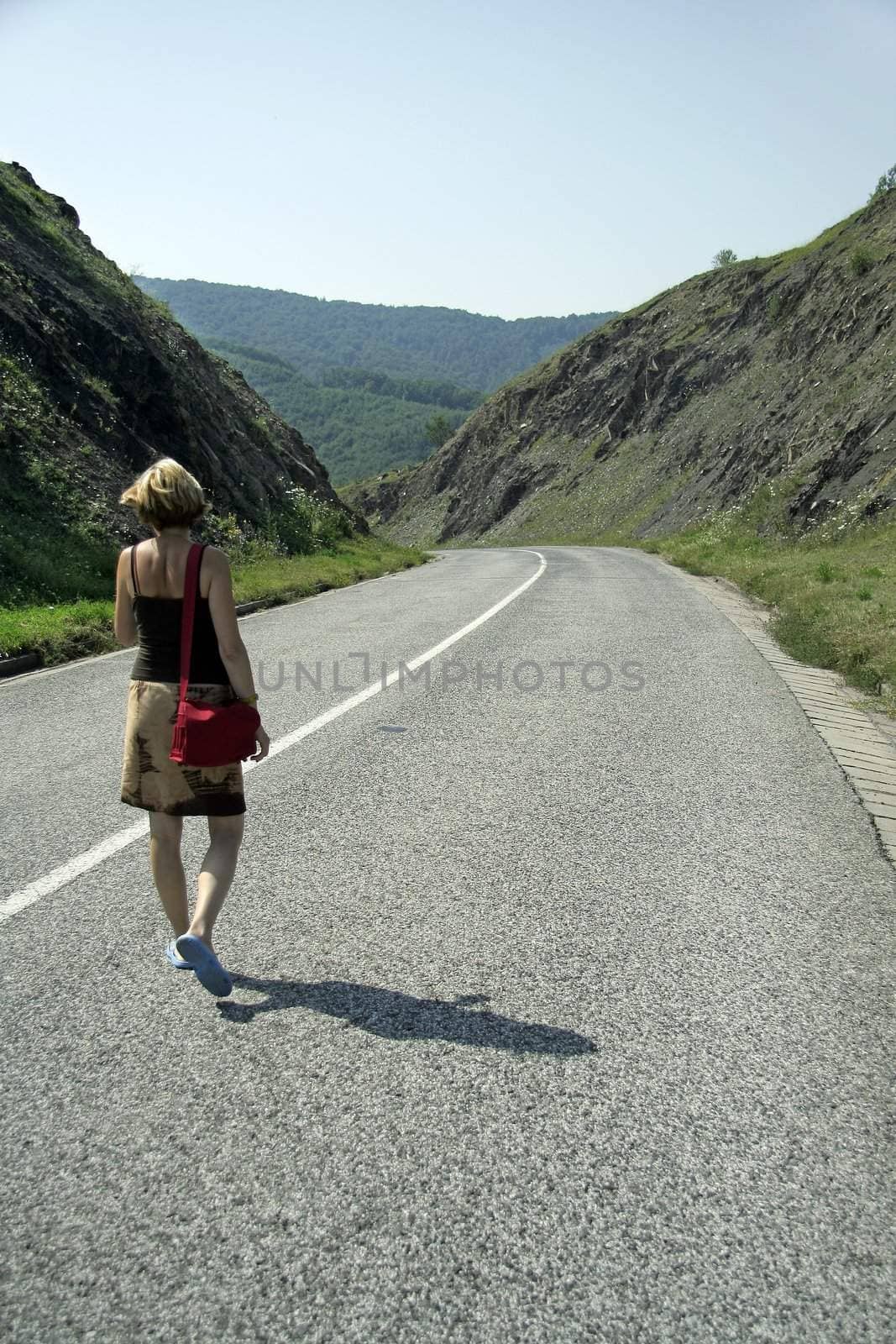 young woman walking an empty road, left curve,