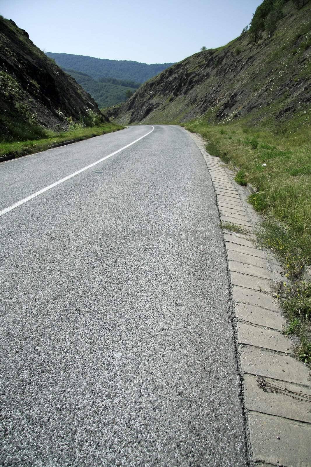 empty road between two hills, left curve in distance