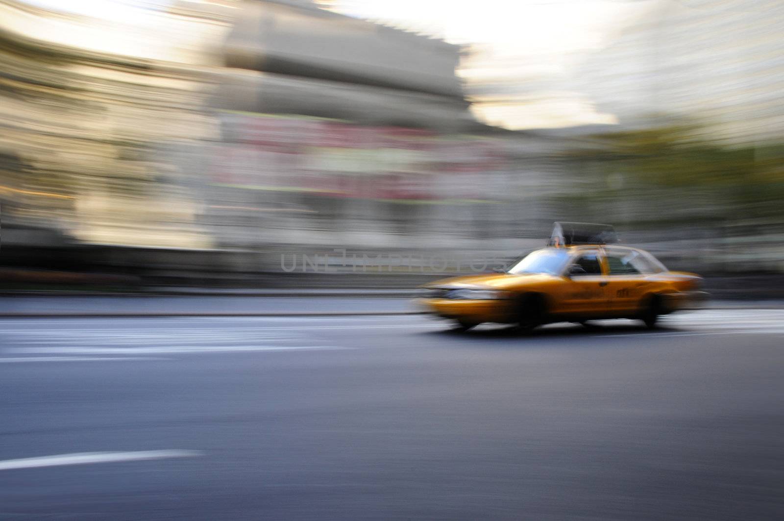 Taxi cab speeding down an urban street in a blur during the daytime
