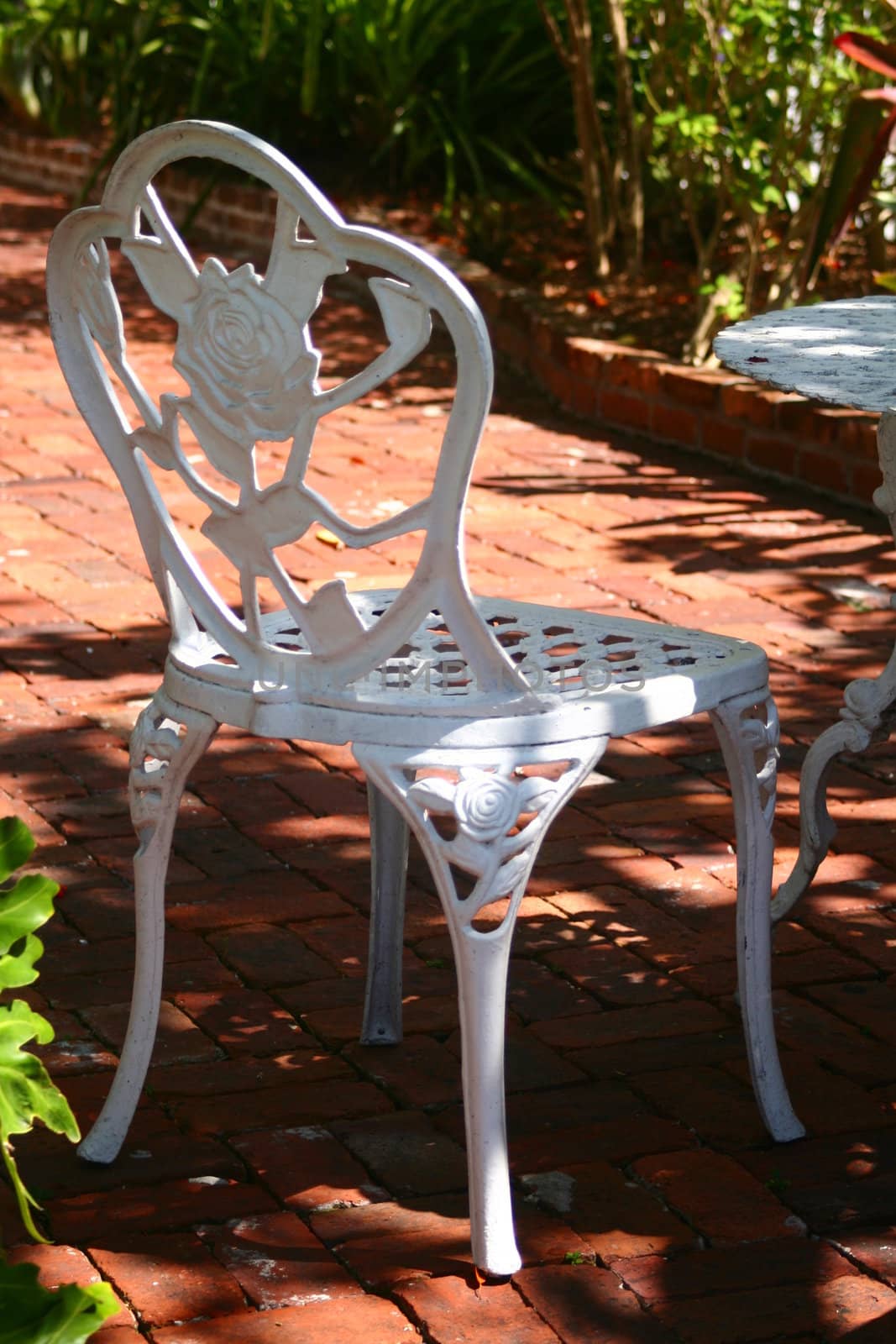 A white, Victoria style chair on a brick patio