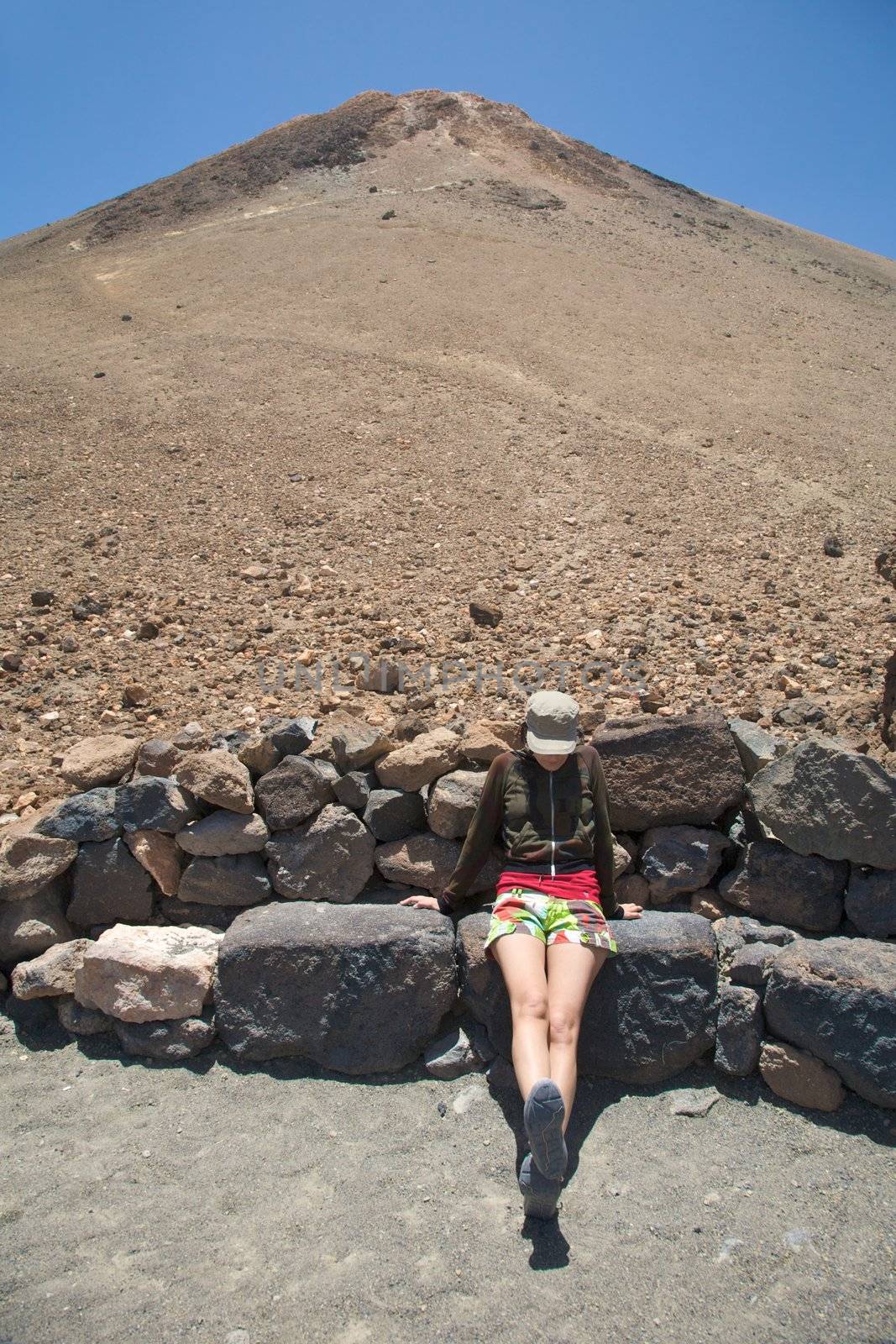 woman sitting down the teide volcano in tenerife spain