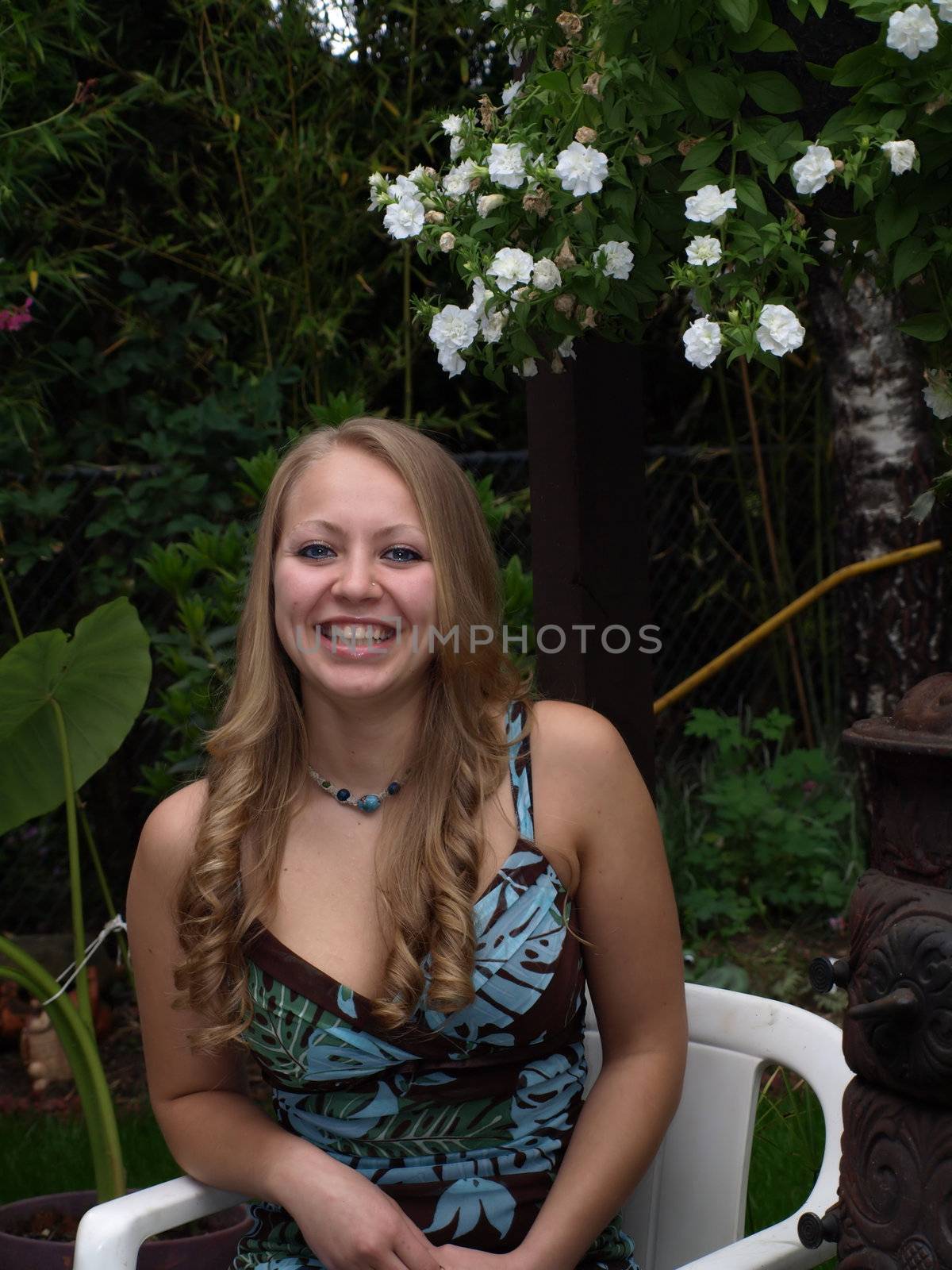 A smiling girl sits in a chair in the garden