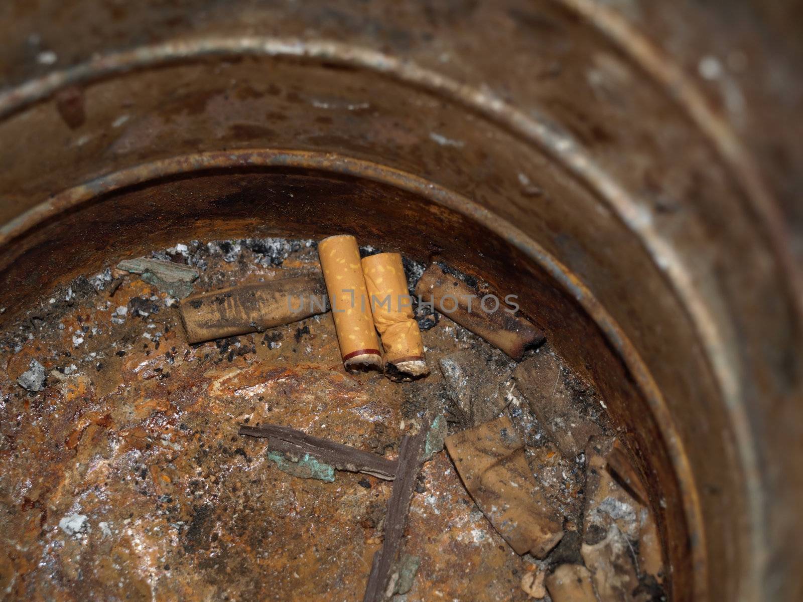A rusty old coffee can with discarded cigarette butts.