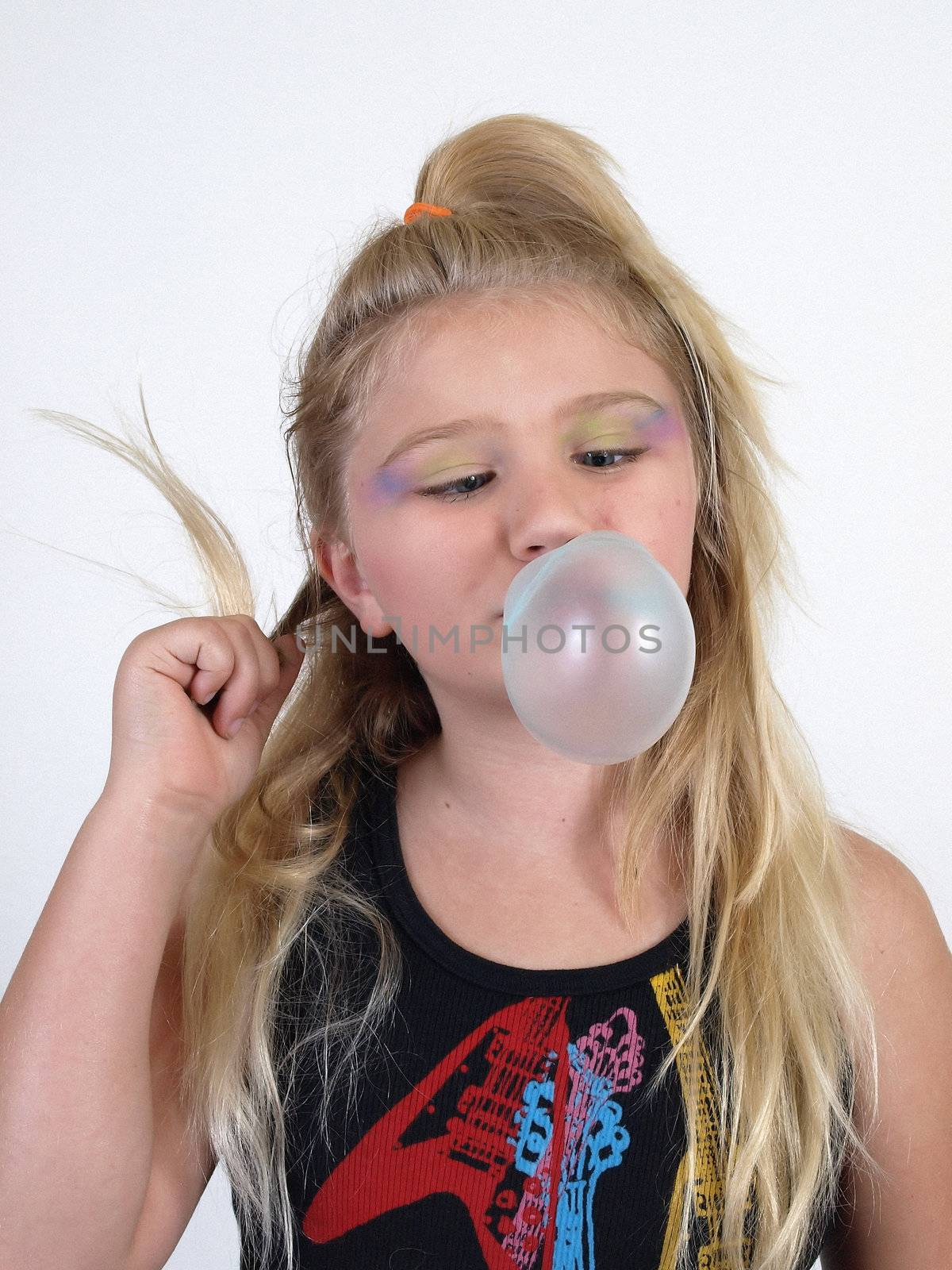 A young blonde girl blowing a bubble and twisting her hair.