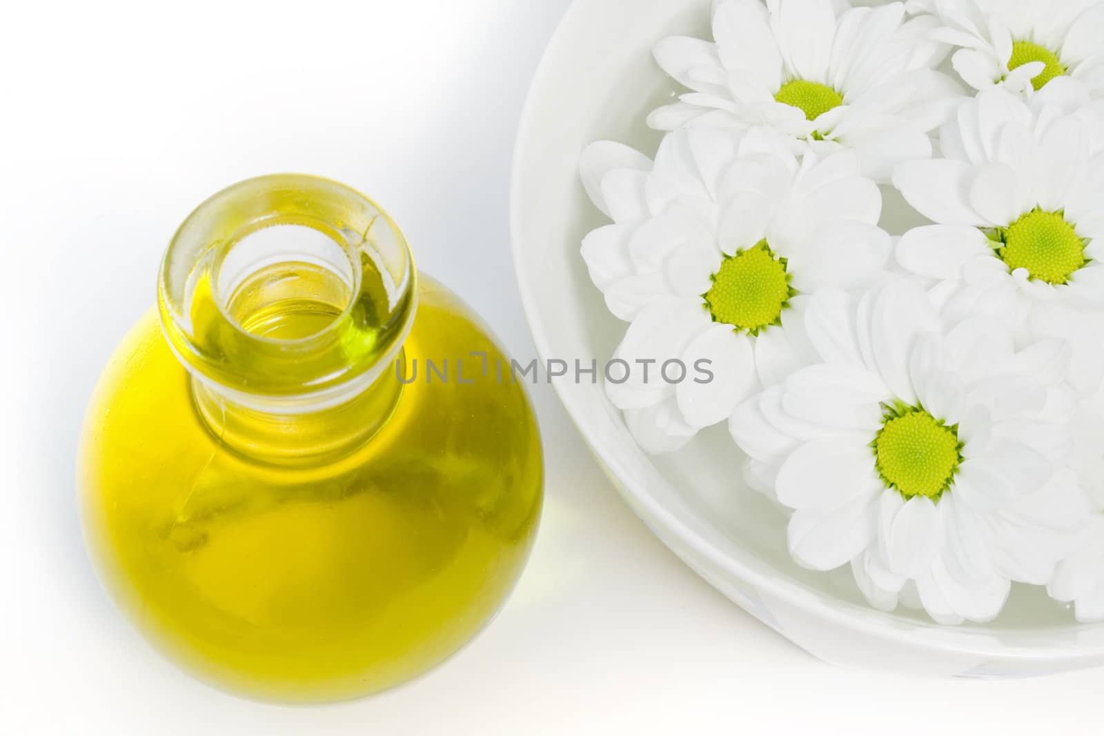 body oil and beautiful white daisies floating in a bowl of water