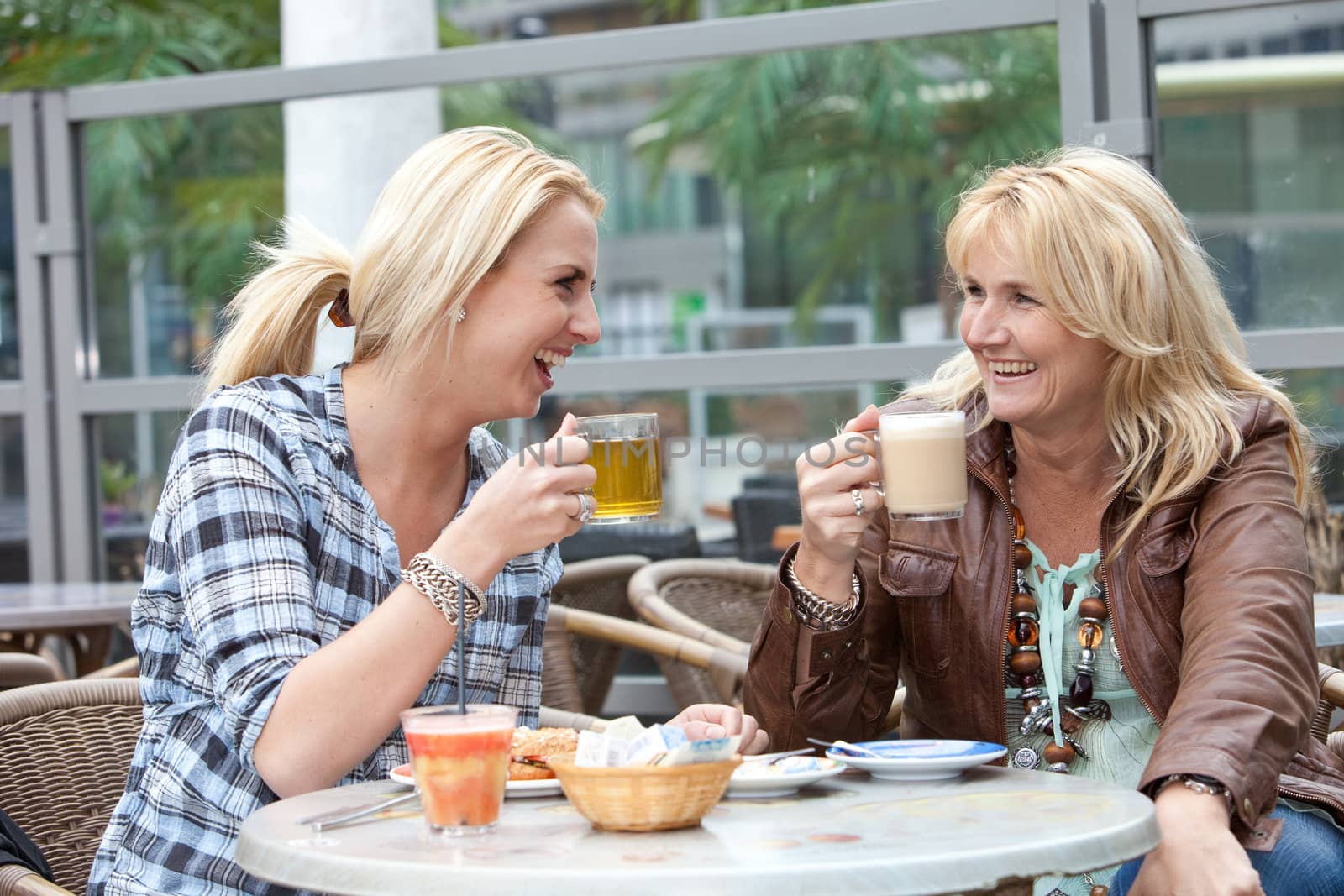 Mother and daughter having tea and coffee laughing together
