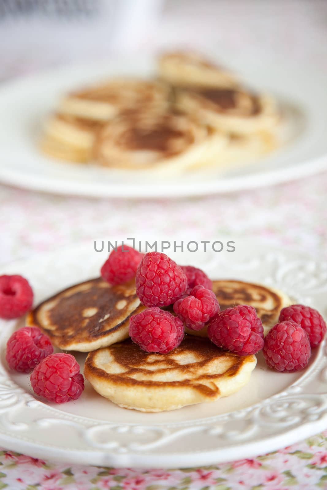 Delicious small pancakes with raspberries on a small plate