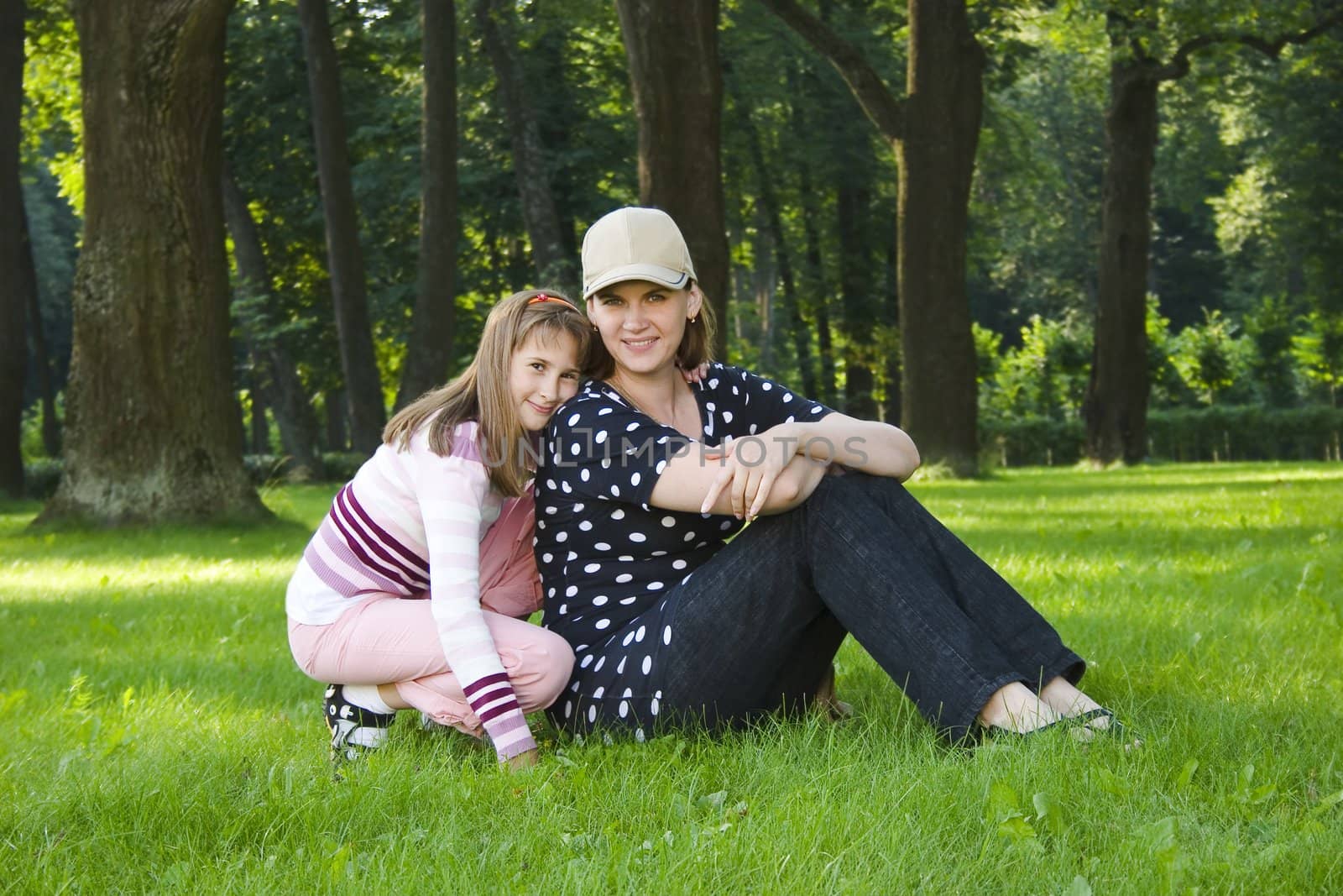 Mother and daughter on lawn in summer's forest.