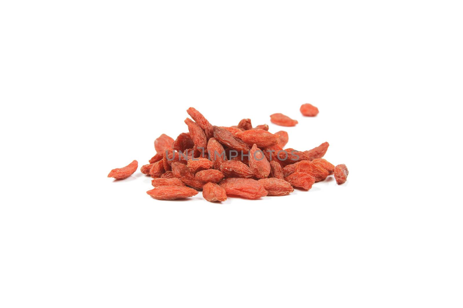 Pile of red dry goji berries on a reflective white background