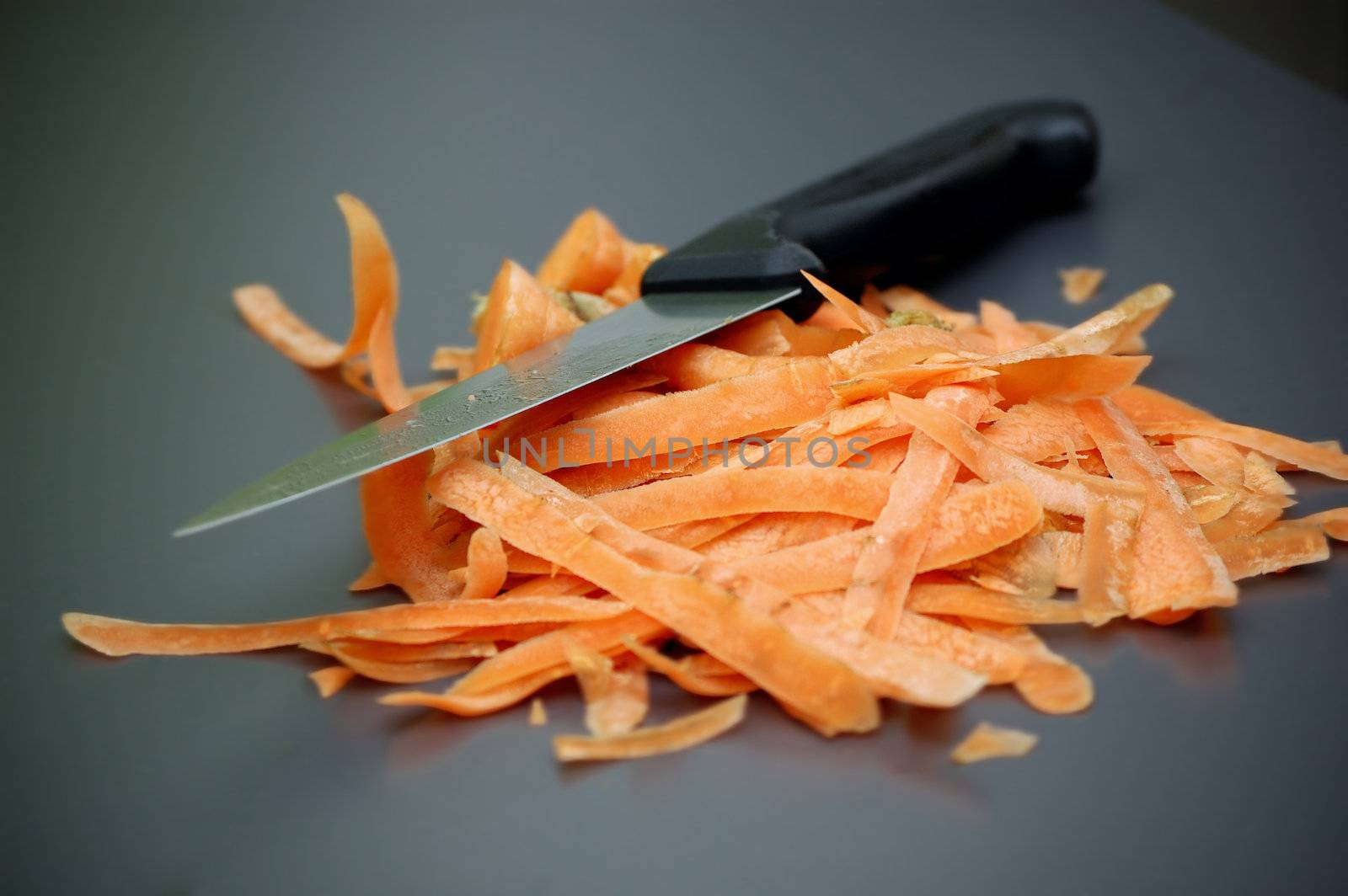 Carrot scraps and knife on a gray kitchen table