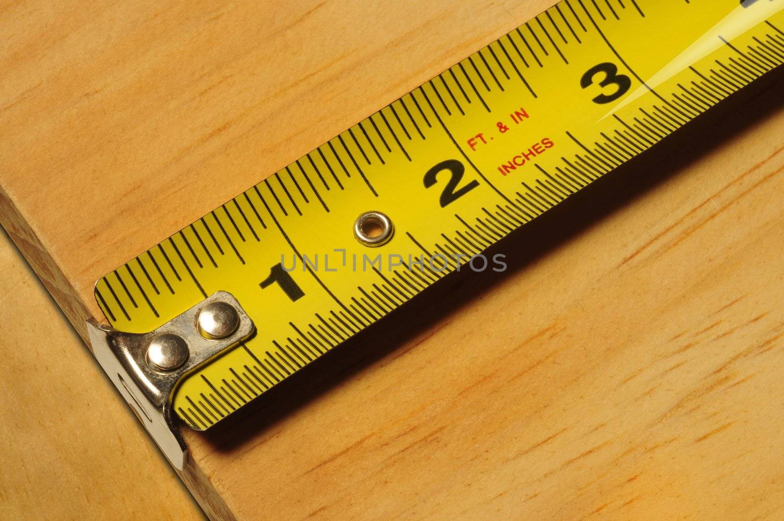 Close-up of a yellow tape measure measuring a piece of wood