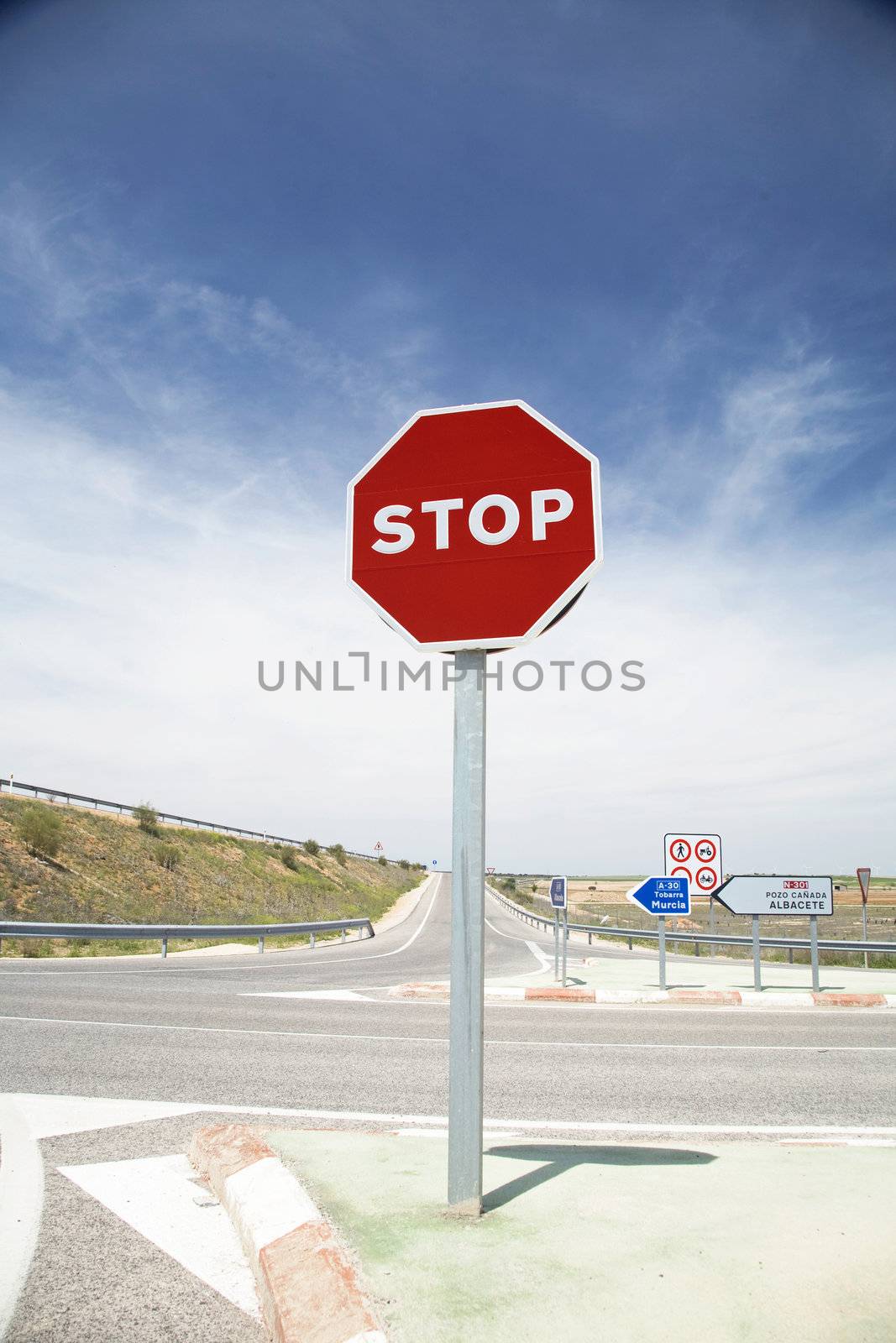 stop sign next to a cross on a spanish highway