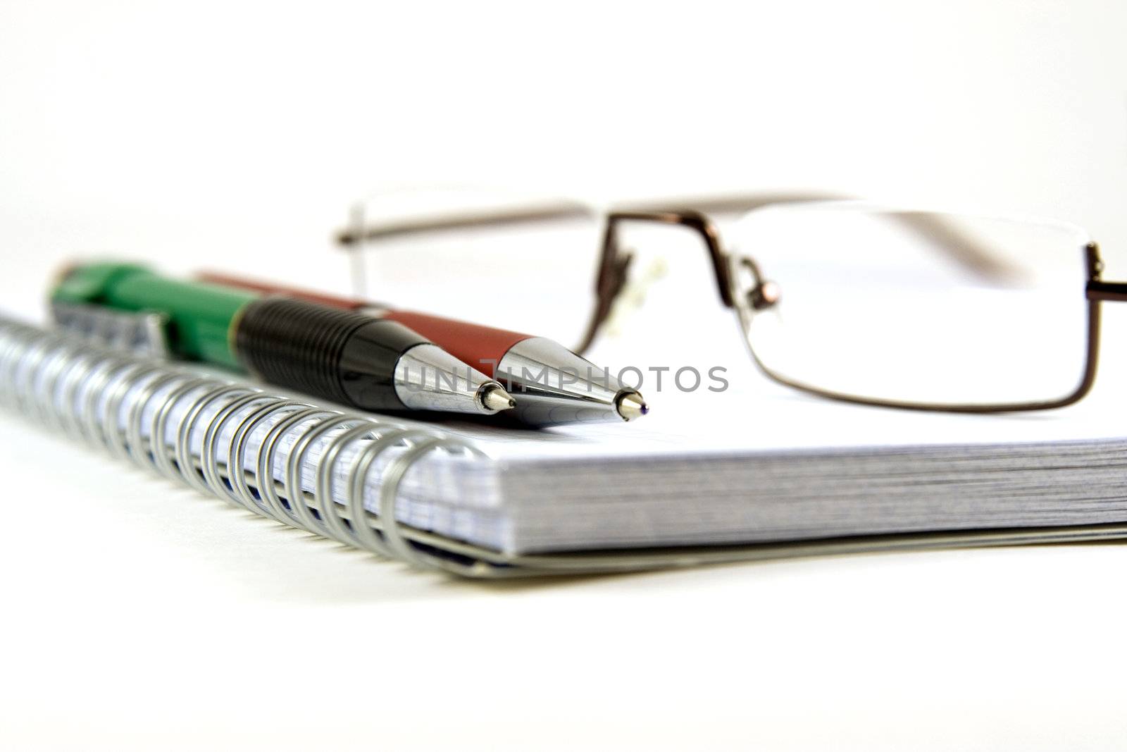 Pen, pencil and glasses on spiral notebook by serpl