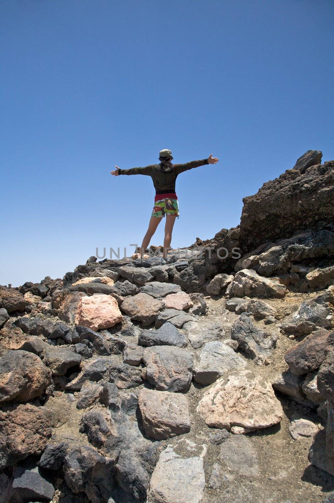 woman with cap open arms near the teide volcano in tenerife spain