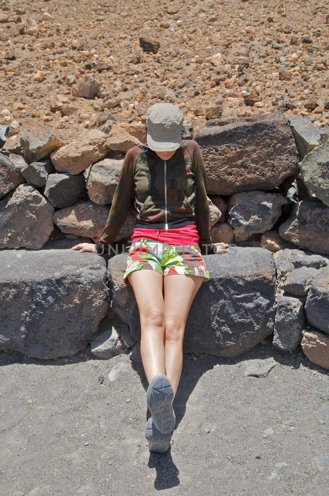woman with shorts resting on a stone sit
