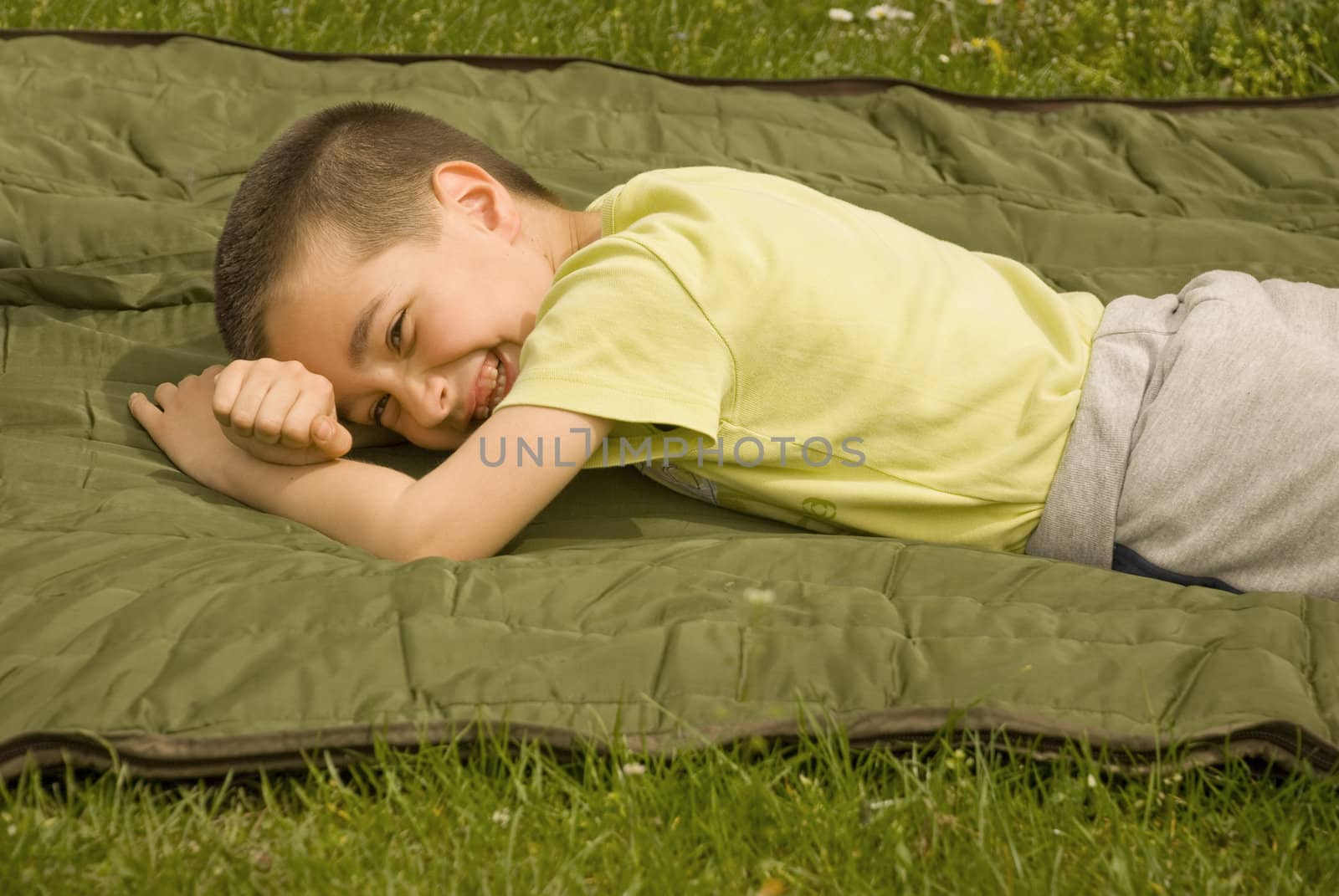 a boy is lying on a blanket and enjoying the sun