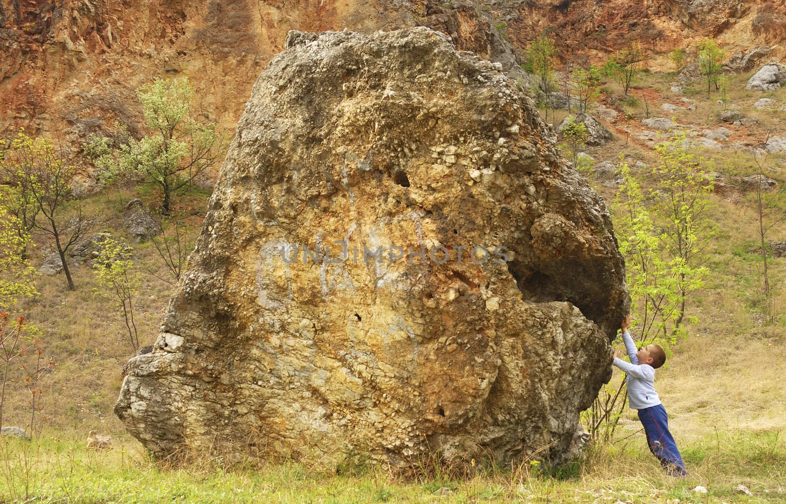 a boy is supporting a rock with his hands