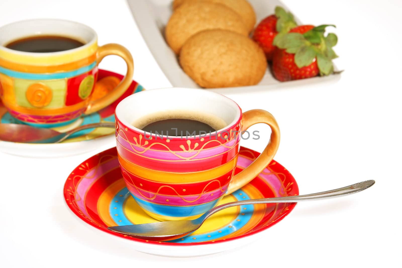 Two colorful cups of coffee, some biscuits and strawberries isolated on white