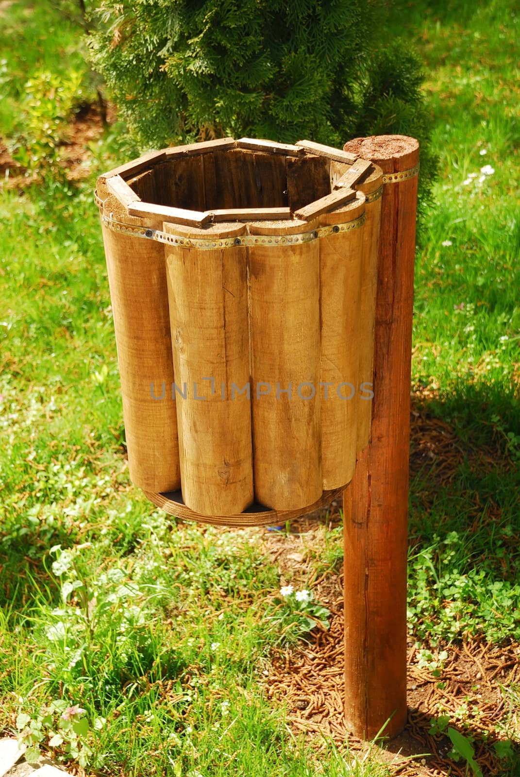 an empty wooden trash can in a green surrounding 