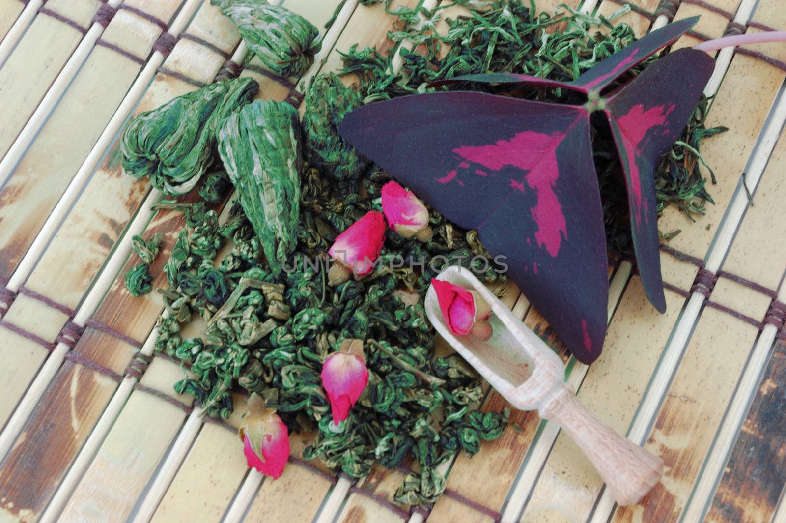 heap of chinese green tea and dried buds of rose