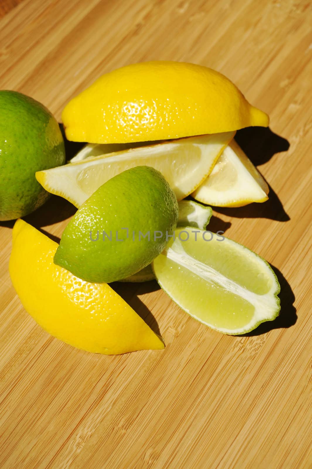 Fresh cut Lemon abd Lime wedges on a Bamboo cutting board.