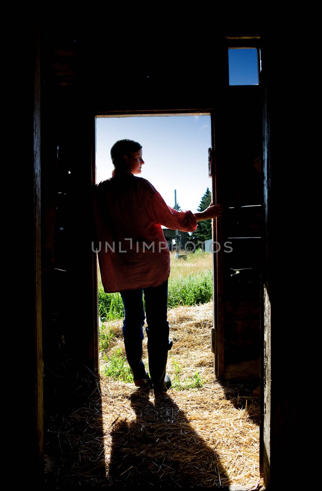 A farm girl standing in a doorway of a barn