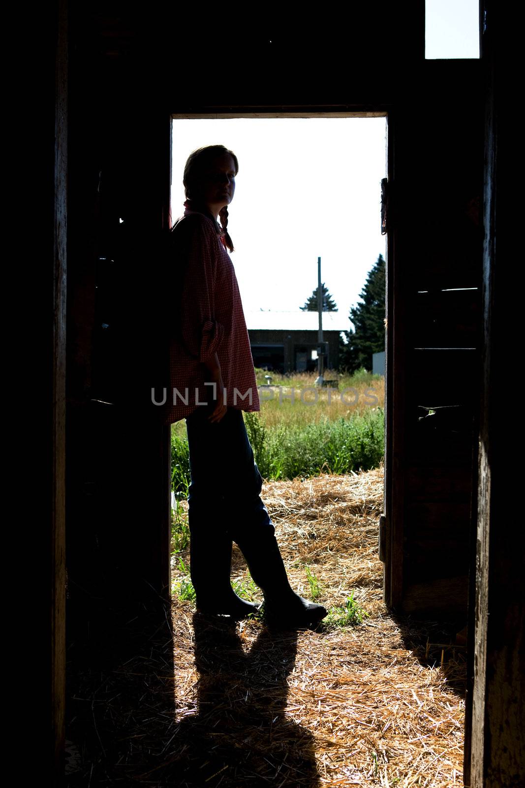 A farm girl standing in a doorway of a barn