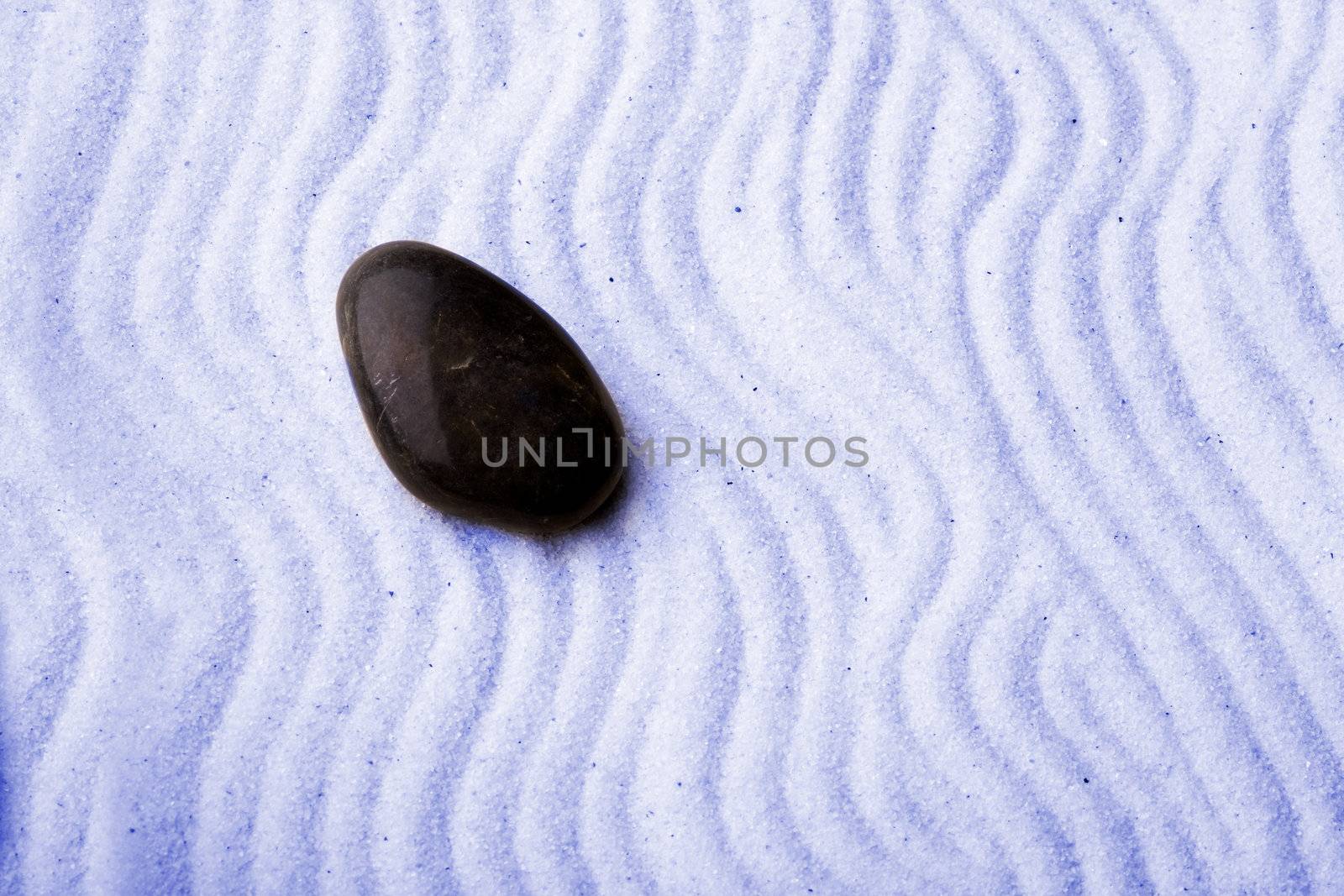 Rock in a zen rock garden with blue sand