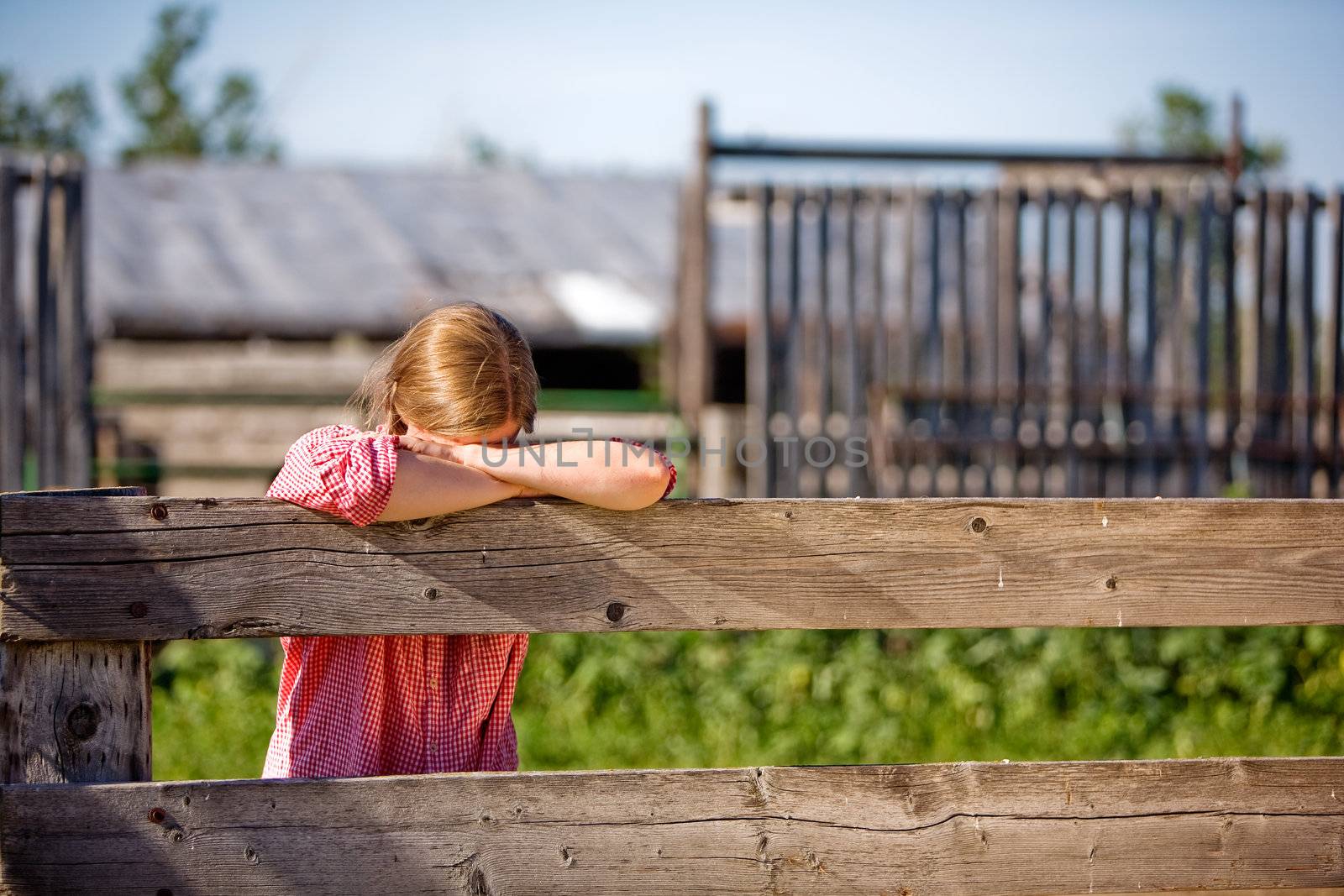 A farm girl resting on the fence
