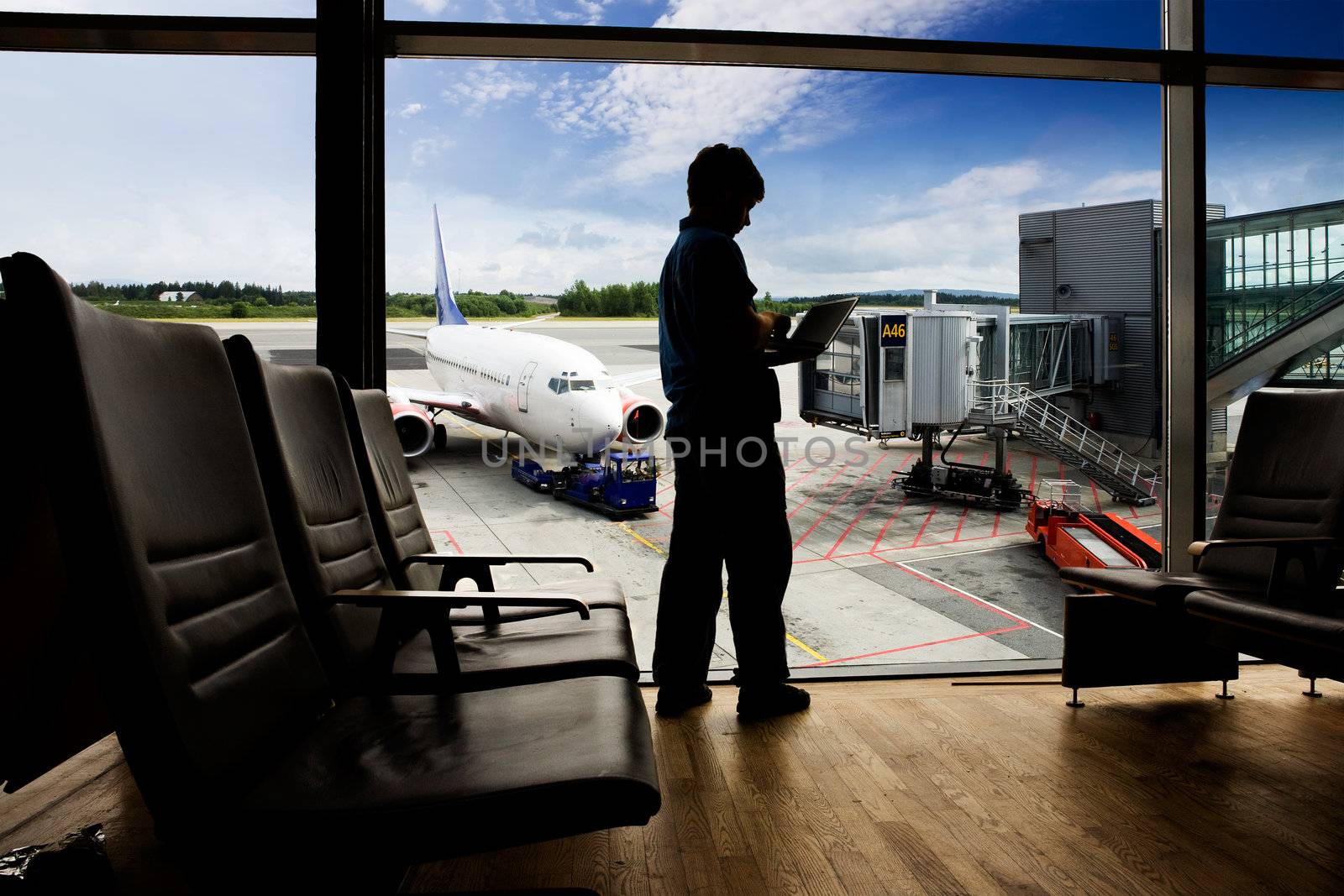 A young man using a laptop in an airport terminal