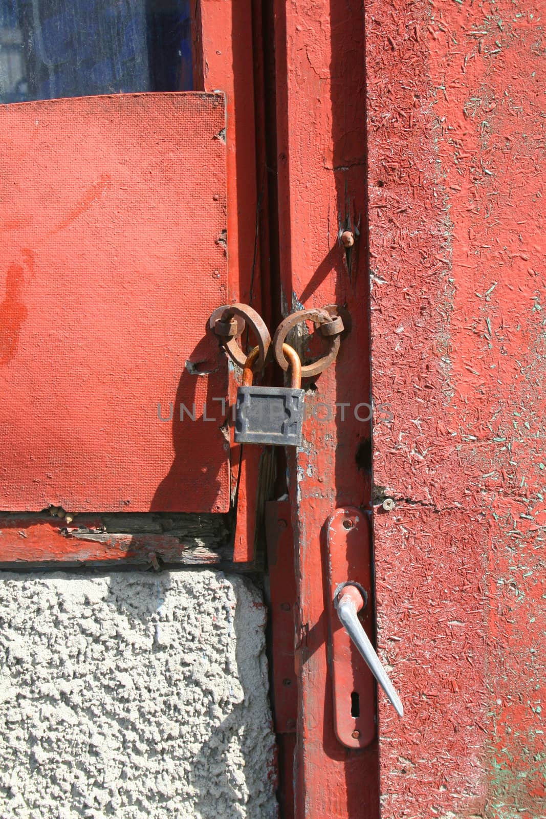 Detail of padlock on weathered red door