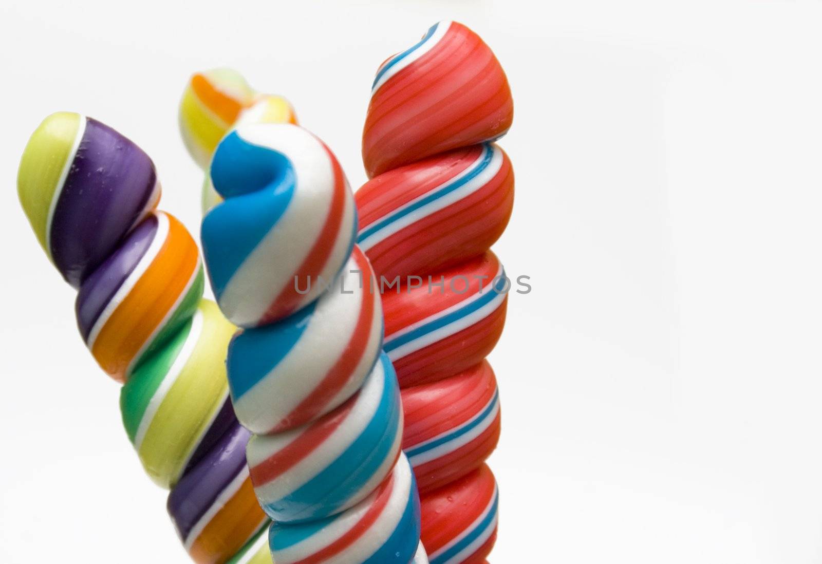 Twisted brightly colored candies on stick against a white background