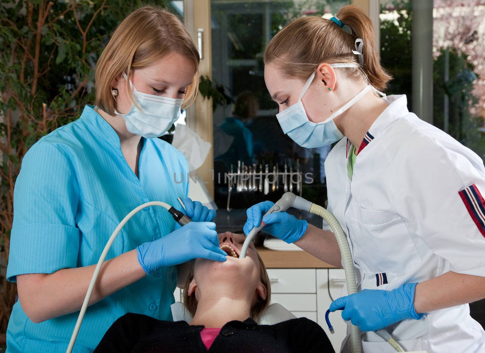 Female dentist working on her patient with her assistent