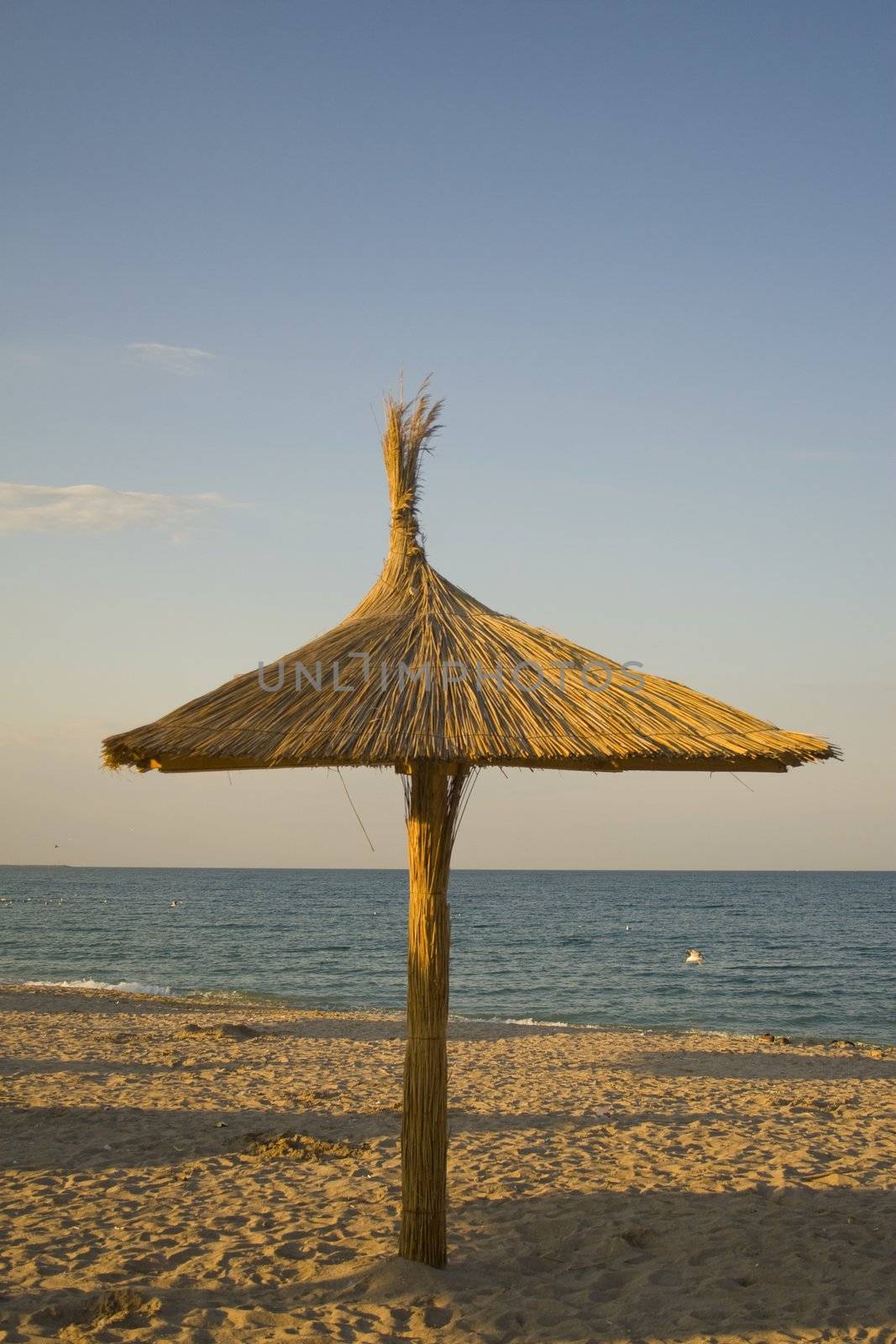 Wood and reed umbrella on picturesque tourist beach