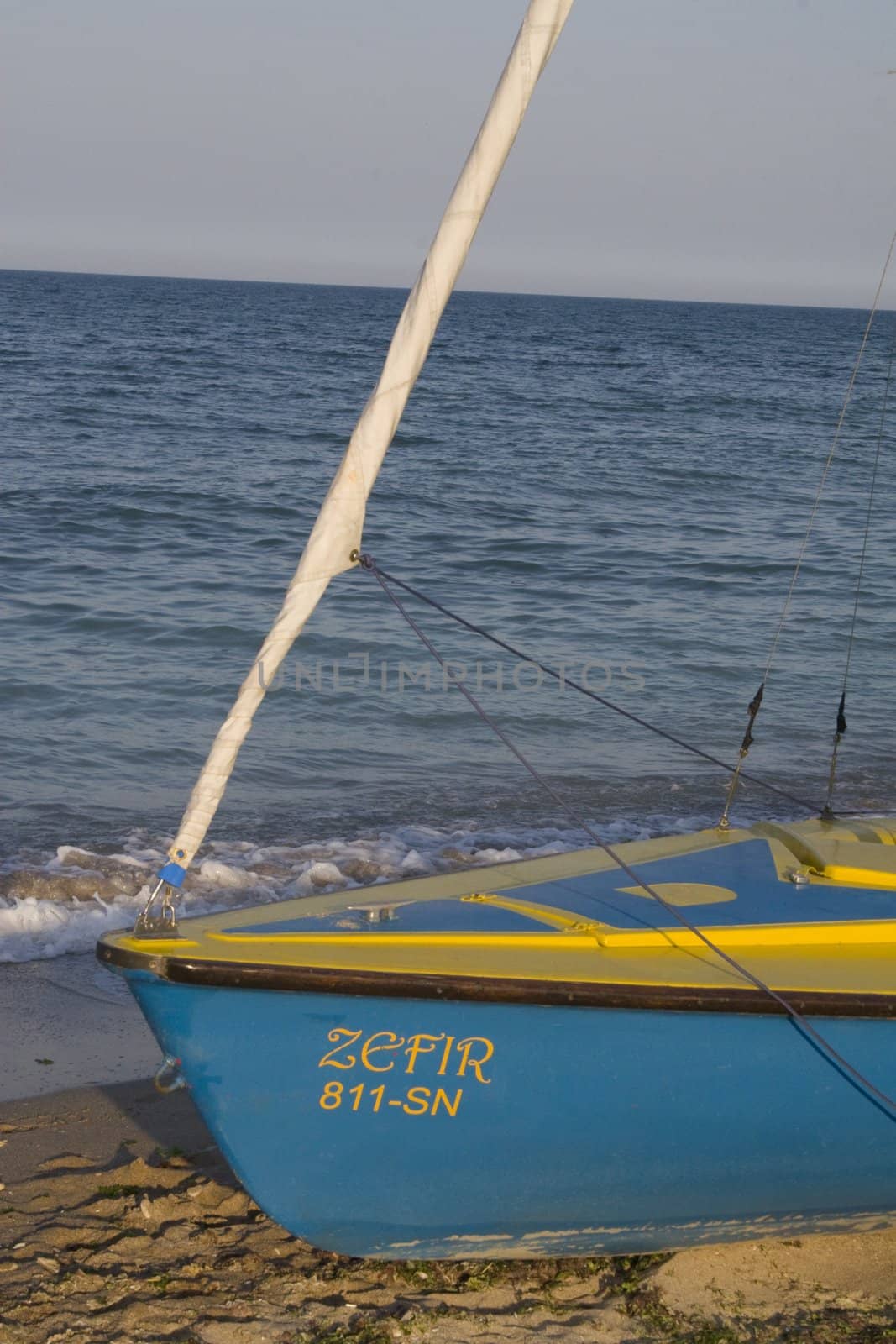 Close-up of beached fishing boat on sand with sea in background