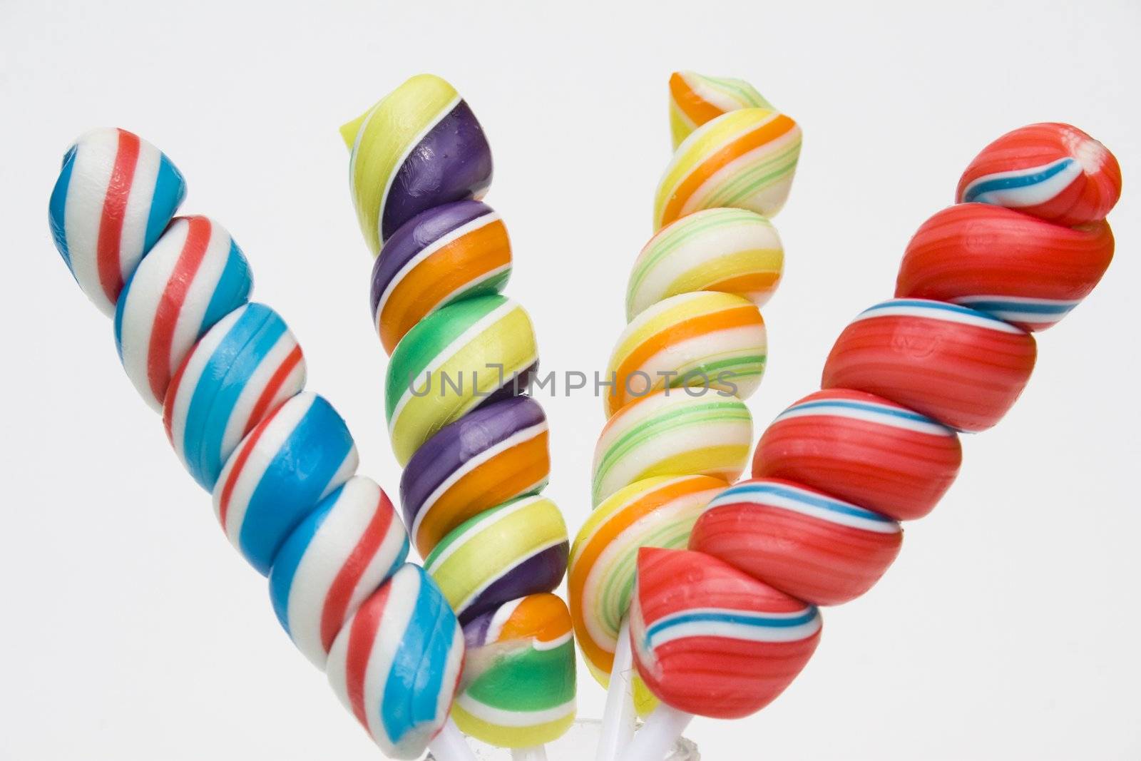 Twisted brightly colored candies on stick against a white background