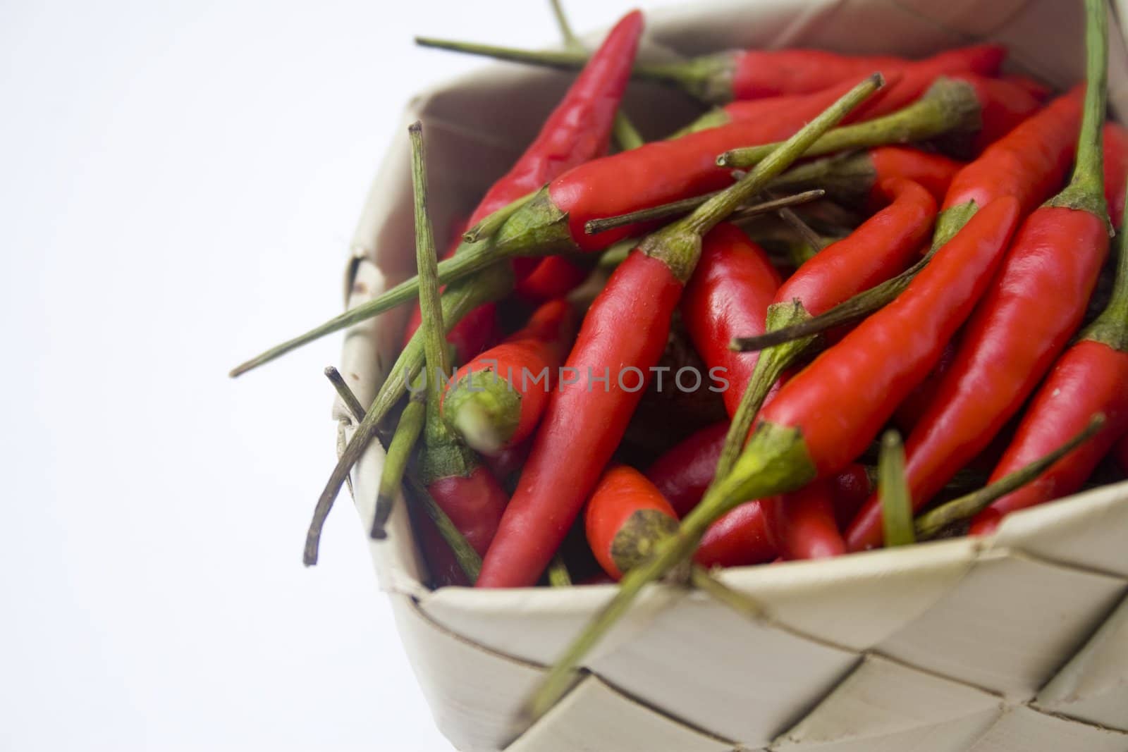 A small woven basket filled with small red chili peppers