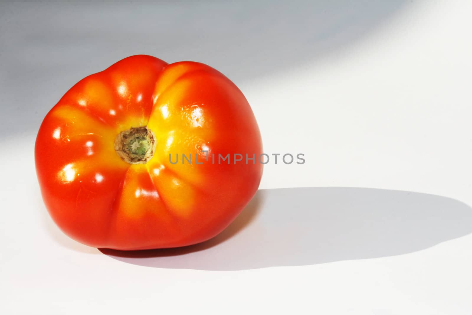 Red tomato with yellow markings on white background