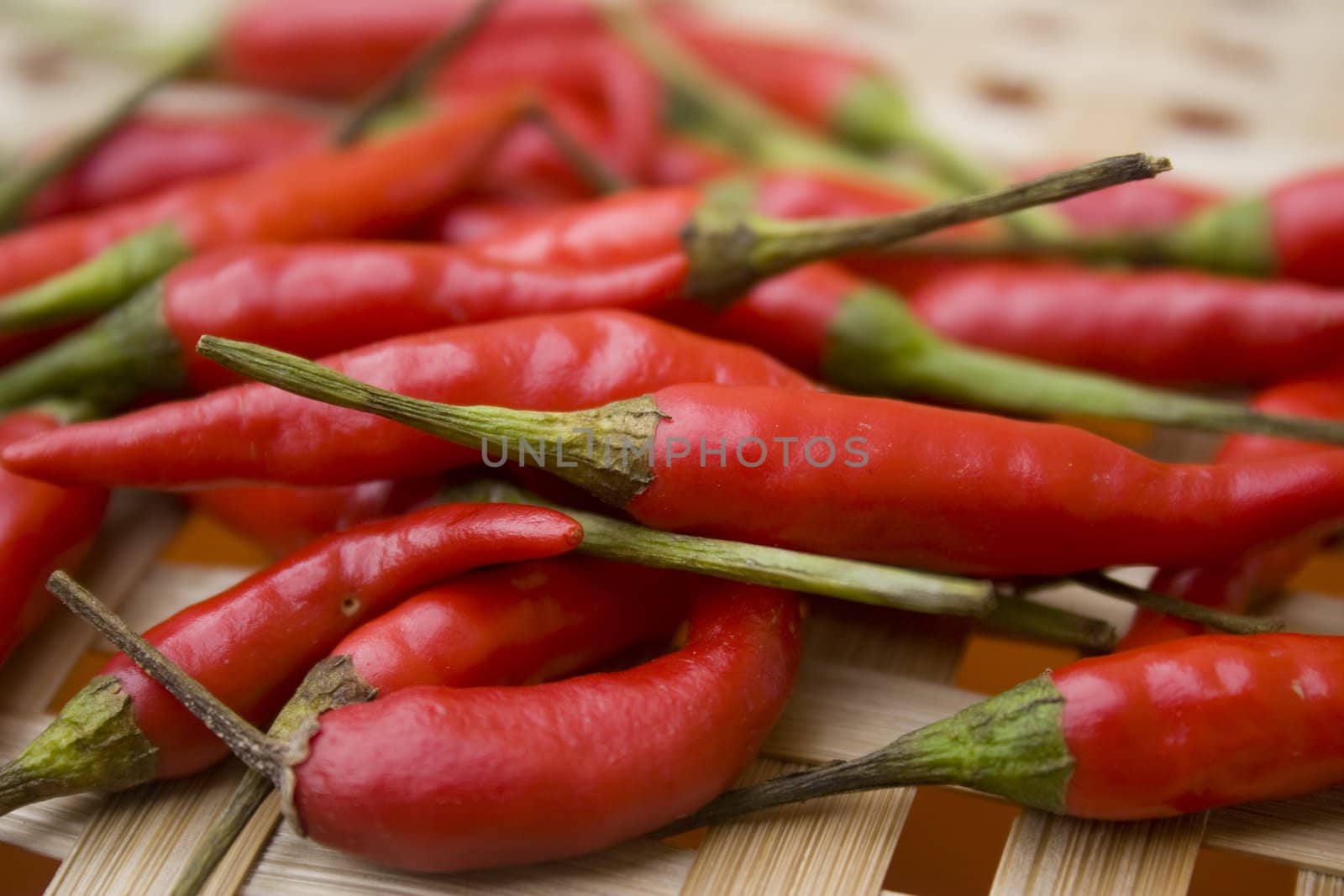 A pile of small red chili peppers on woven basket