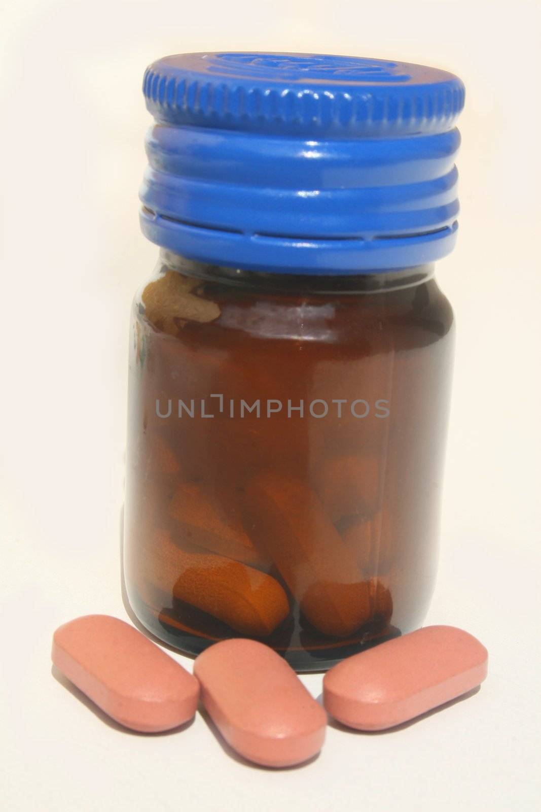 Bottle of pills with pink ones in front