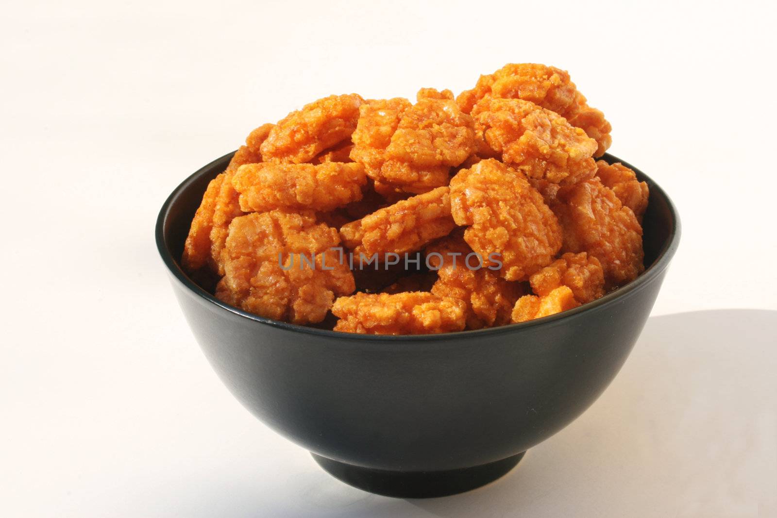 Bowl of asian spicy crackers against white background